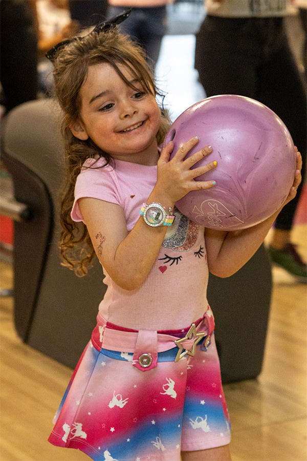 Boys and Girls Club Member holding pink bowling ball