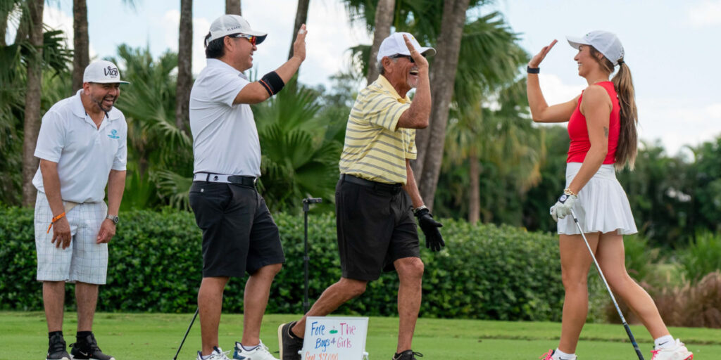 Four participants of the Golf Tournament high-fiving during the golf match