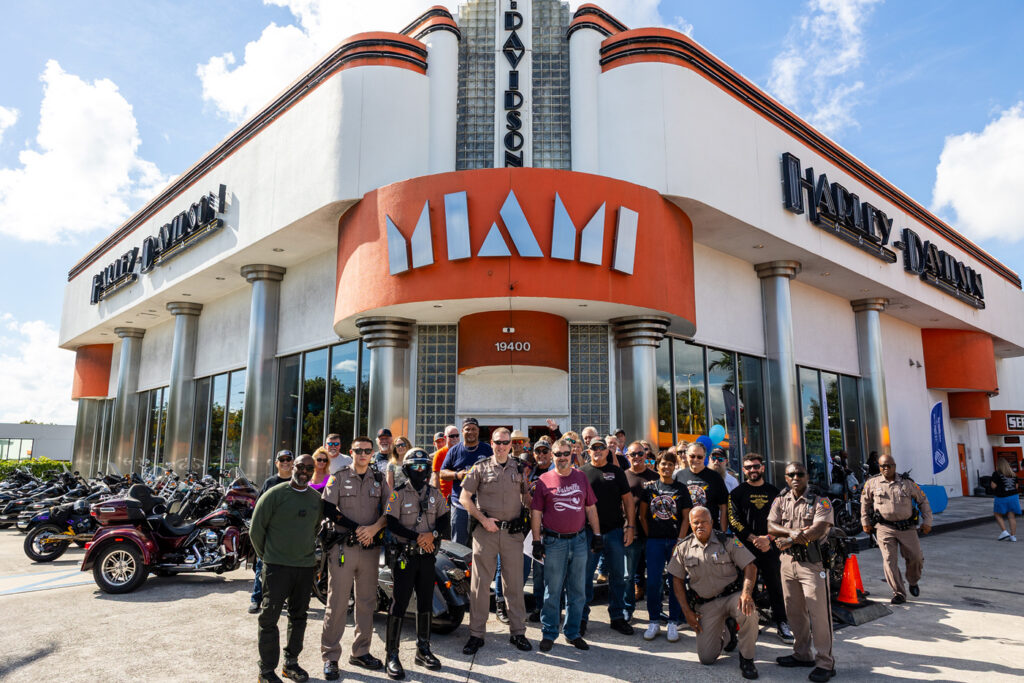Bikers and local police officers posing together in front of the Peterson's Harley Davidson as part of the biker's bash.