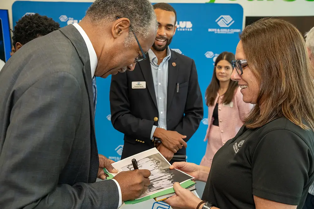 Dr. Ben Carson Smiling as he signs a picture for an attendee of the event.
