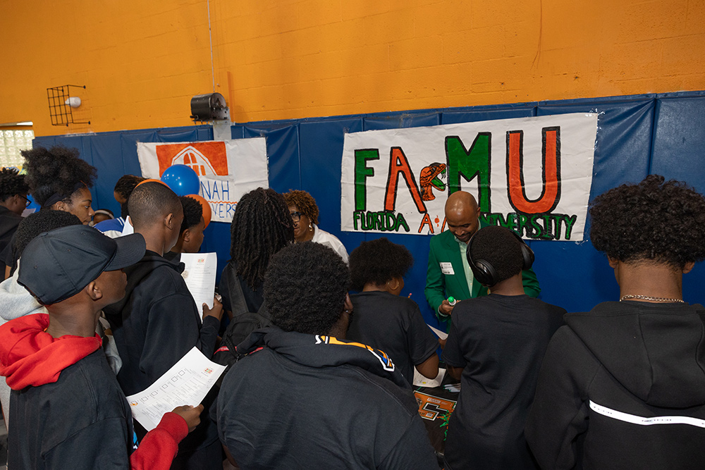 BGCBC Club members receiving information from each of the college booths. A sign reading 'F A M U', an acronym for the Florida A&M University.