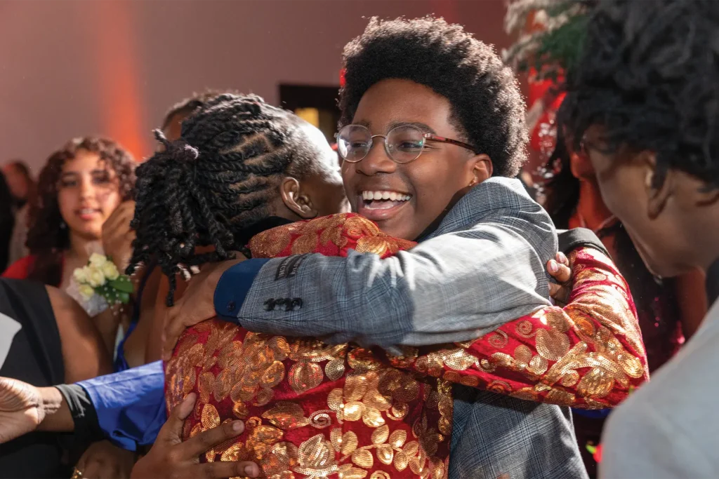 Jakeclaude, the 2026 Youth of the Year, smiling and hugging his fellow club member.