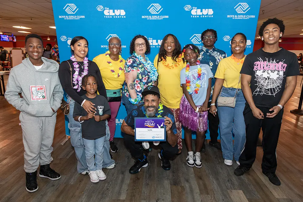 A group picture of attendees at the Bowling for kids event posing in front of a BGCBC branded backdrop.