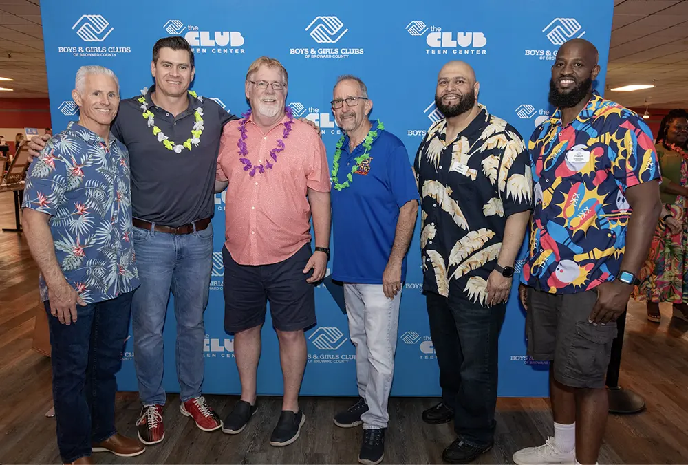 BGCBC Administrative staff, a BGCBC Club Director, and others who made the event possible posing in front of a branded backdrop featuring 'The Boys & Girls Clubs of Broward County' logo and 'The Club ' logo at the Bowling for Kids Event.