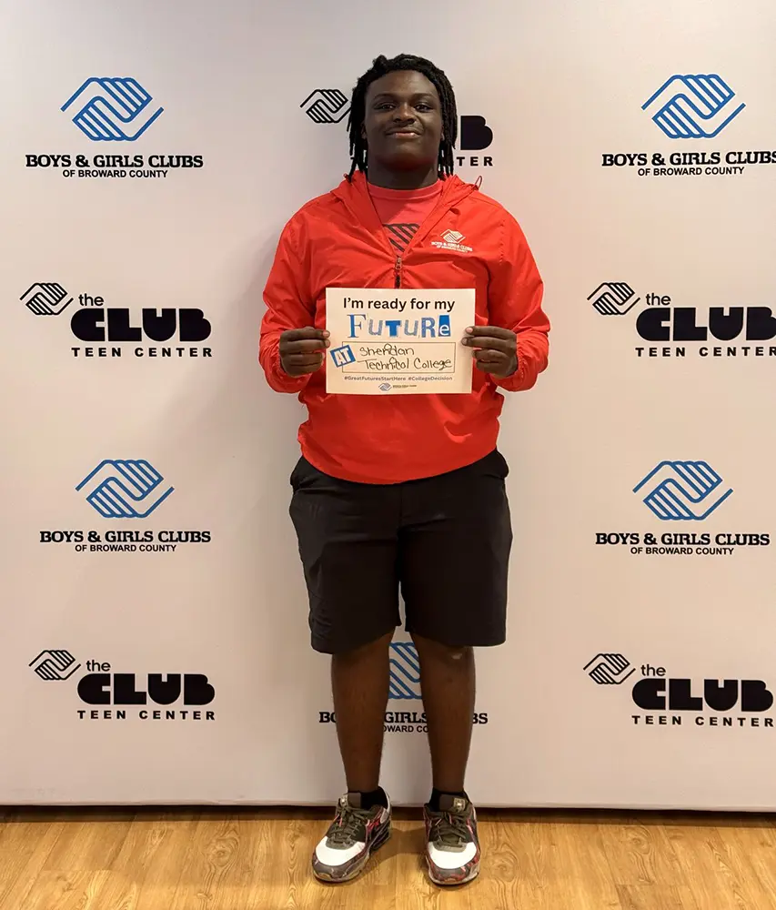A BGCBC Club member holding a sign that reads Sheridan Technical College.