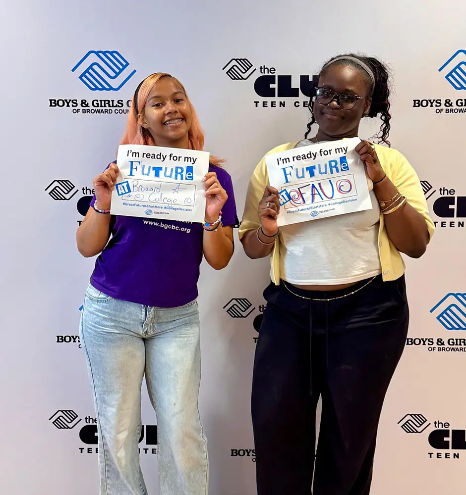 Two BGCBC Club members each holding up their signs. The first has a sign that reads Broward College and the second club member has a sign that reads FAU for Florida Atlantic University