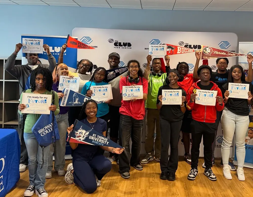 A group picture of BGCBC Teen members smiling as they hold up signs with the initials of the college they want to attend.