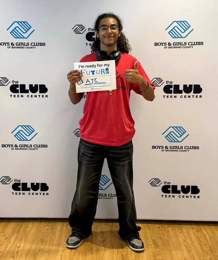 A BGCBC Club member holding up a sign that reads ATC for Atlantic Technical College