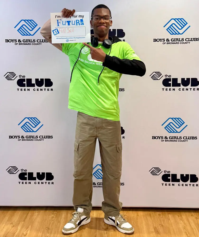 A BGCBC member proudly pointing to their sign, which reads "I'm ready for my future at Full Sail University