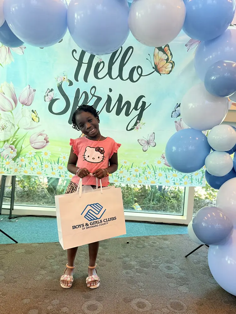 A BGCBC club member holding a white Boys & Girls Clubs of Broward county bag.