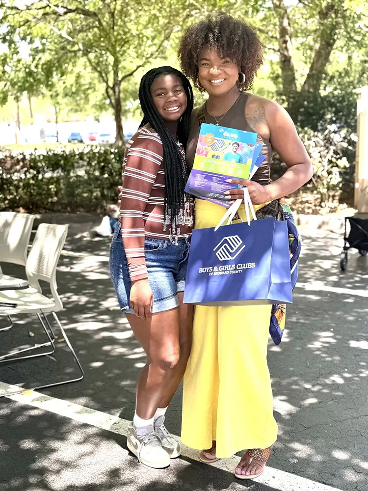 Attendees of the event posing together smiling and holding a blue BGCBC bag.
