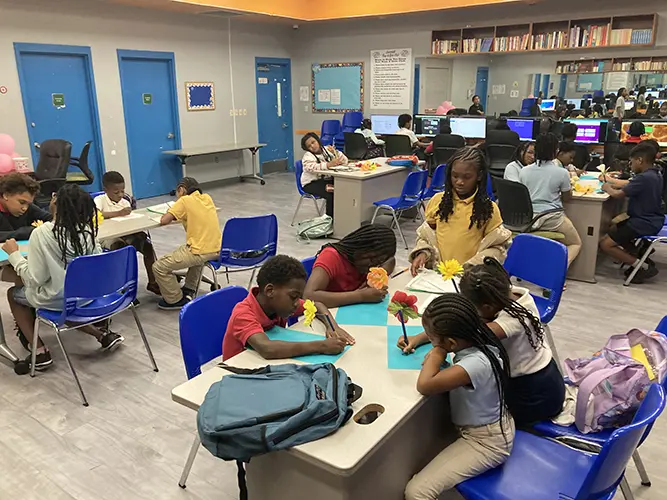A room of BGCBC Club members focused as they work on school work with pencils decorated to look like flowers.