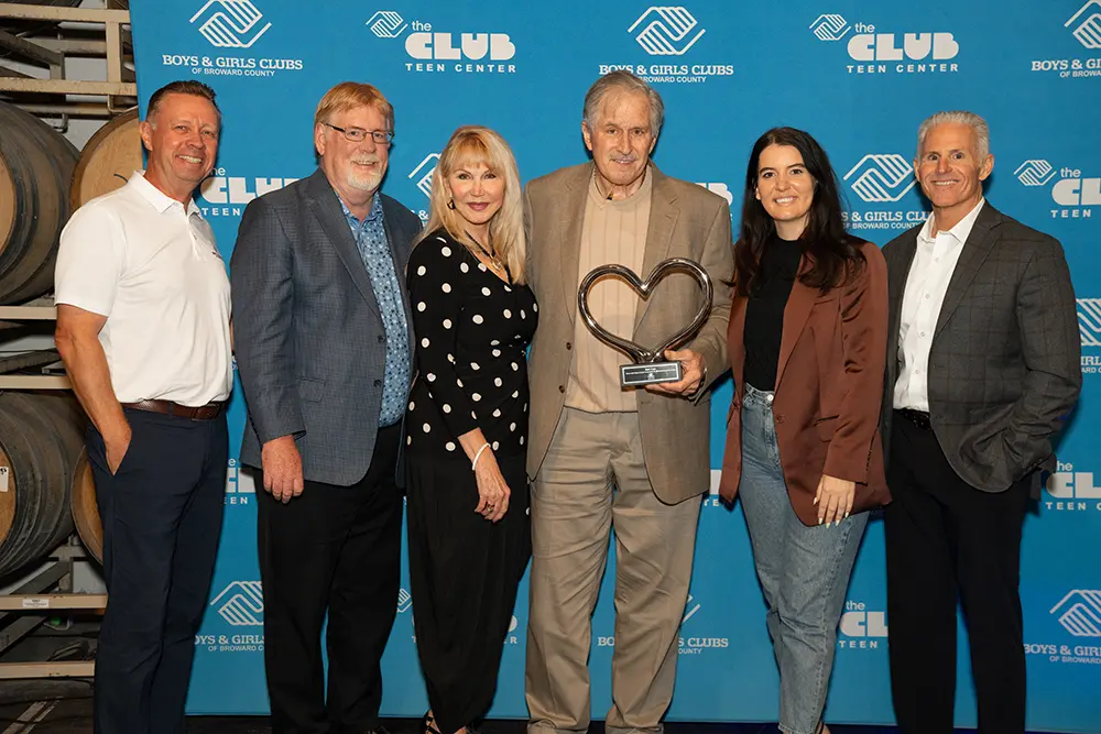 Bob Case holding his Gratitude Award posing alongside Debi Case, Matt Organ, Chris Gentile, Peter Oldbury, and Nicole Melendez