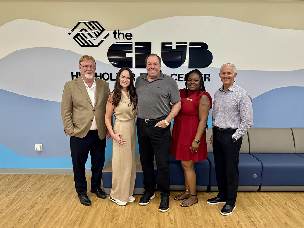 Christy and Larry Hierhozler posing in front of the "The Club" sign with BGCBC administrative staff.