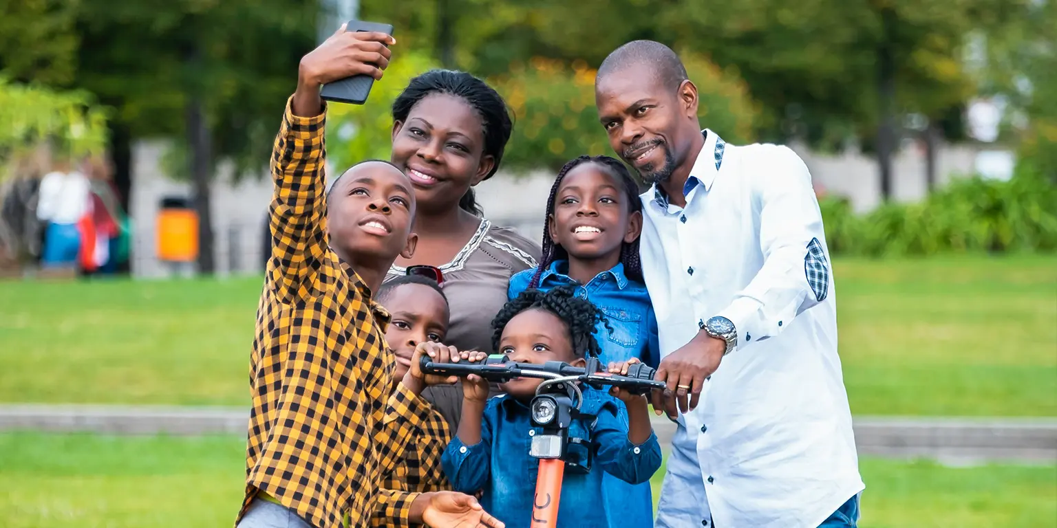 A family posing together on a scooter at a park.